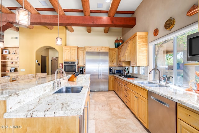 kitchen with sink, backsplash, a center island with sink, and stainless steel appliances