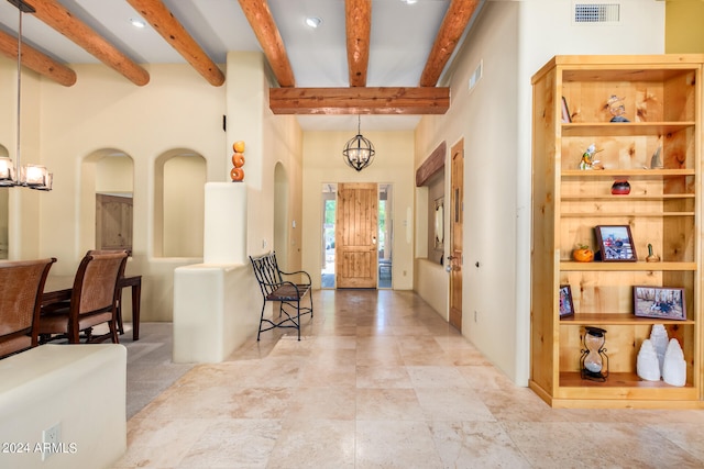 tiled entrance foyer with beamed ceiling, a towering ceiling, and an inviting chandelier