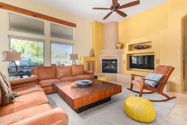 living room featuring a towering ceiling, ceiling fan, and a large fireplace