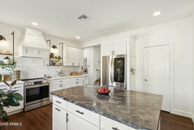 4525 N 66th St Unit 1, Scottsdale, AZ 85251 - kitchen featuring appliances with stainless steel finishes, premium range hood, dark wood finished floors, white cabinets, and decorative backsplash