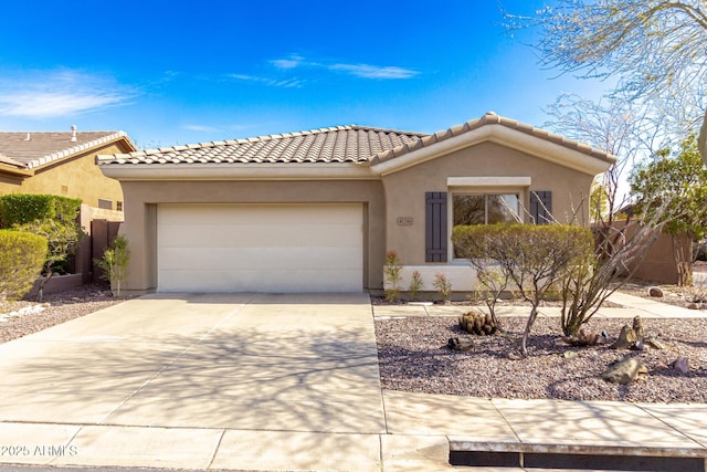 view of front facade with a tile roof, driveway, an attached garage, and stucco siding