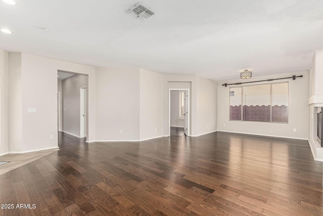 unfurnished living room with recessed lighting, wood finished floors, visible vents, baseboards, and a glass covered fireplace