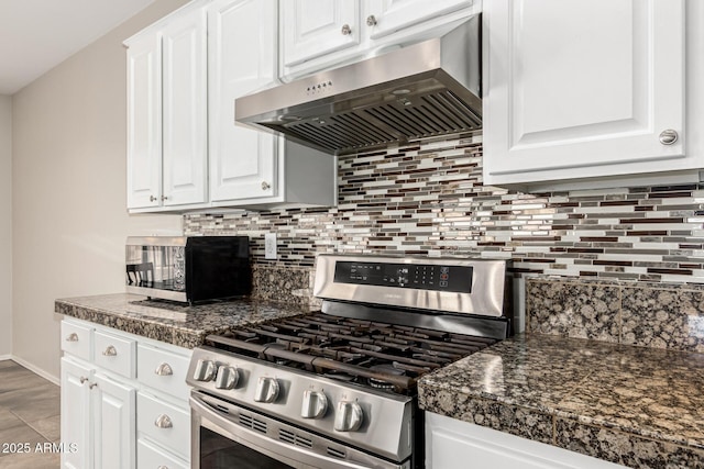 kitchen with dark countertops, range hood, stainless steel appliances, and backsplash