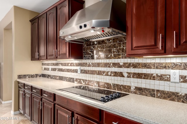 kitchen featuring tasteful backsplash, wall chimney range hood, light tile patterned floors, black electric stovetop, and dark brown cabinets