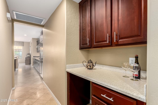 kitchen with light tile patterned floors, baseboards, reddish brown cabinets, and light countertops