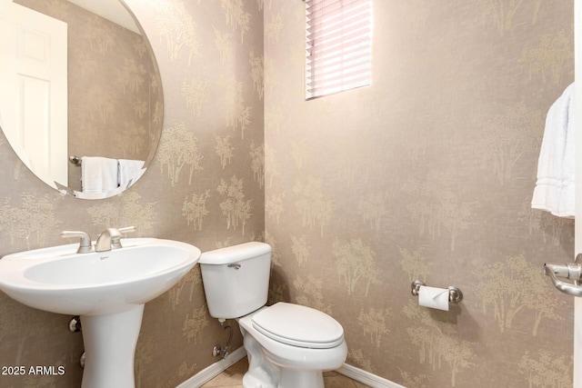 half bathroom with wallpapered walls, toilet, and baseboards