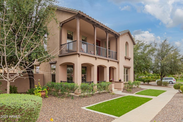 view of front facade with a balcony and stucco siding