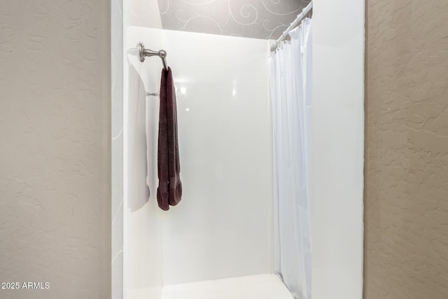 bathroom featuring curtained shower and a textured wall