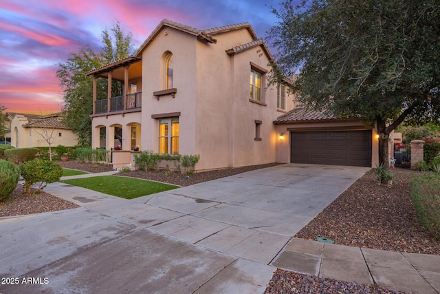 mediterranean / spanish-style house with stucco siding, a tiled roof, concrete driveway, and a balcony