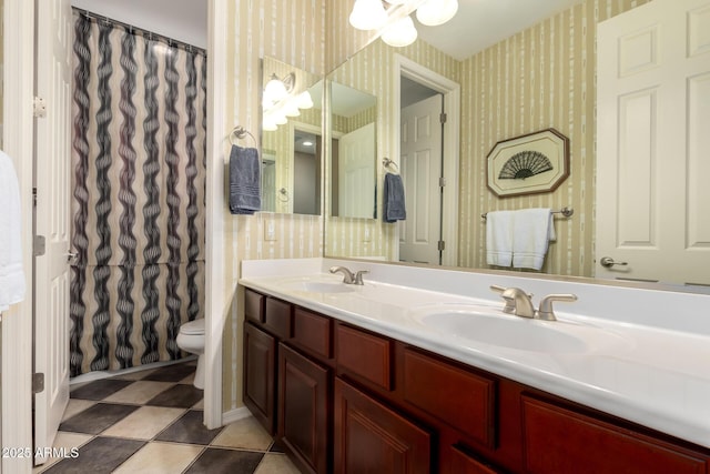 bathroom featuring double vanity, toilet, wallpapered walls, and a sink