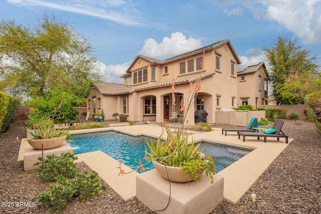 back of property with a tile roof, a patio area, and stucco siding