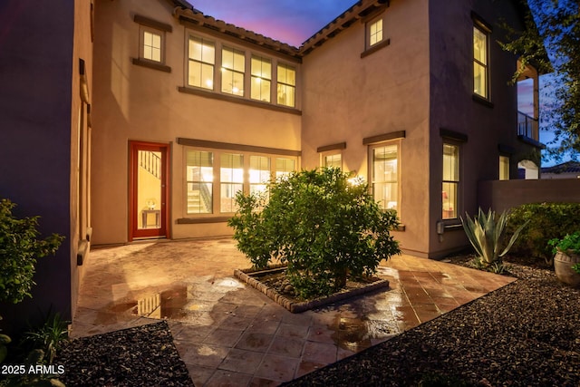 rear view of property with a patio, a tile roof, and stucco siding