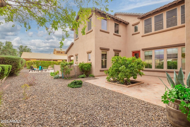 back of property with stucco siding and a patio