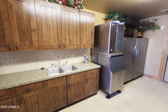 kitchen featuring light countertops, tasteful backsplash, freestanding refrigerator, and a sink