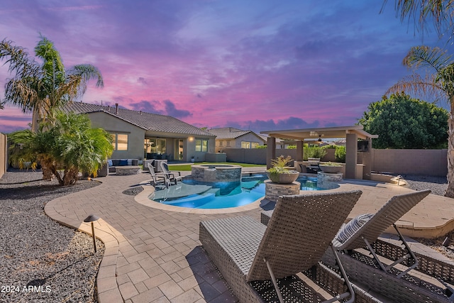 pool at dusk featuring a patio, an in ground hot tub, and ceiling fan