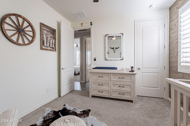 bedroom featuring light carpet and wooden walls