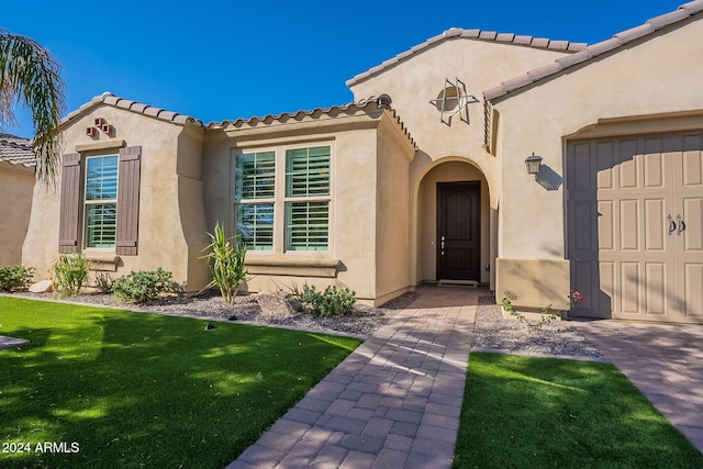 doorway to property with a yard and a garage