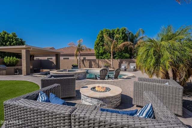 view of patio / terrace featuring a pool with hot tub and a fire pit