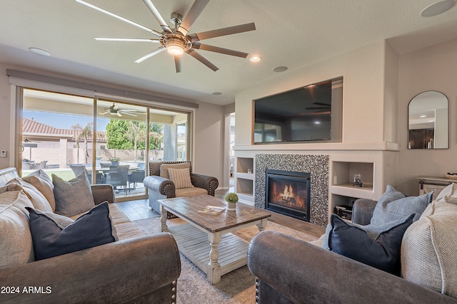 tiled living room featuring ceiling fan, built in features, and a fireplace