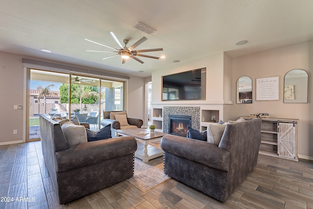 living room with hardwood / wood-style floors, a tiled fireplace, a textured ceiling, and ceiling fan