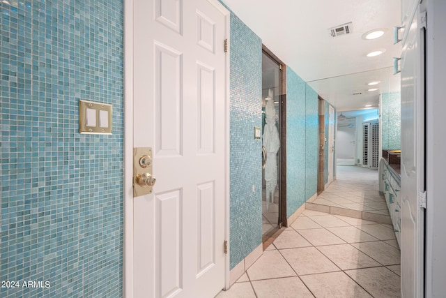 hallway with light tile patterned flooring and tile walls