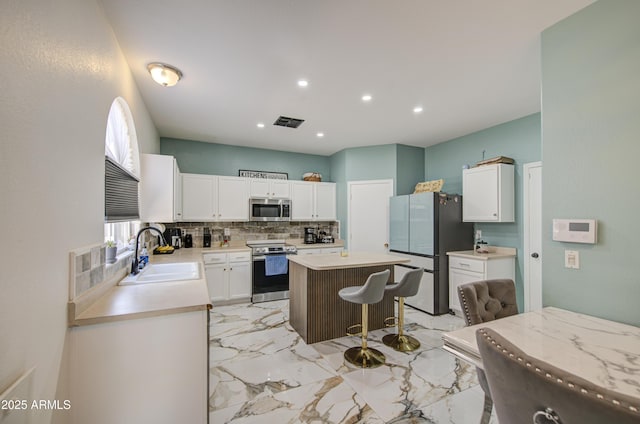 1107 E Ln Salle St, Phoenix, AZ 85040 - kitchen featuring appliances with stainless steel finishes, tasteful backsplash, a kitchen island, light countertops, and recessed lighting