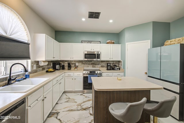 1107 E Ln Salle St, Phoenix, AZ 85040 - kitchen with stainless steel appliances, light marble finish floors, white cabinetry, backsplash, and light countertops
