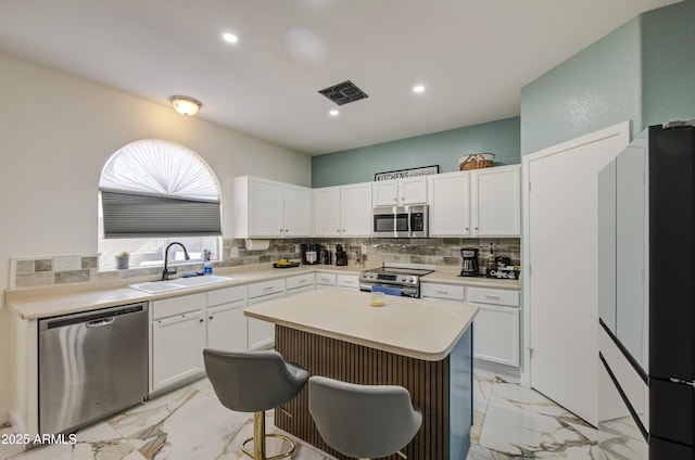 1107 E Ln Salle St, Phoenix, AZ 85040 - kitchen with appliances with stainless steel finishes, backsplash, white cabinetry, light marble finish flooring, and recessed lighting