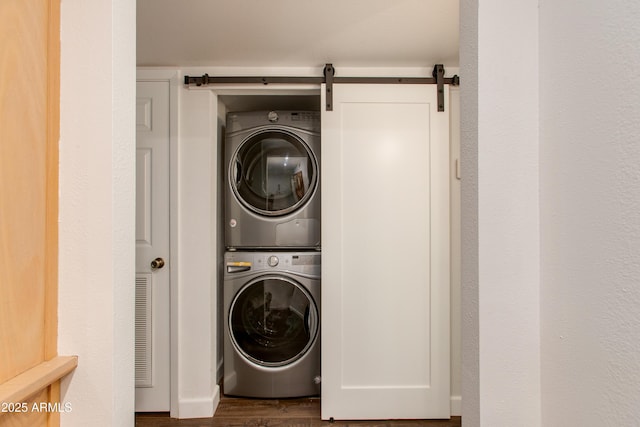 clothes washing area with laundry area, stacked washing maching and dryer, and wood finished floors