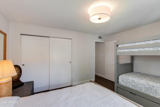 bedroom with baseboards, visible vents, a closet, and a textured ceiling