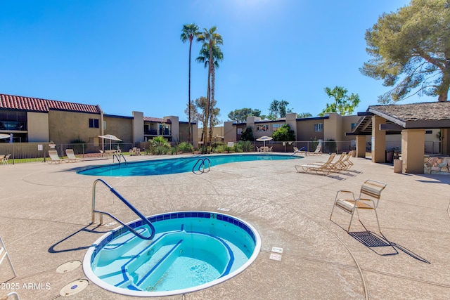 pool featuring a patio area, a community hot tub, fence, and a residential view