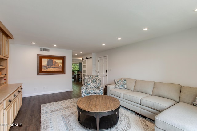 living area with recessed lighting, a barn door, visible vents, and dark wood-style flooring