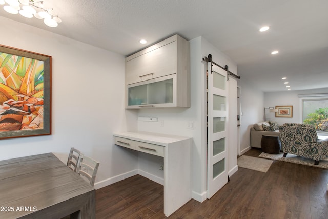 kitchen with dark wood-type flooring, baseboards, light countertops, a barn door, and recessed lighting