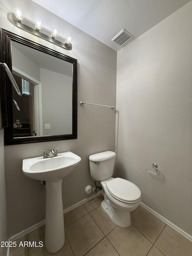 bathroom featuring baseboards, visible vents, toilet, and tile patterned floors