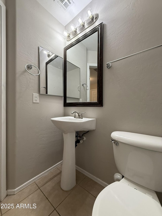 bathroom featuring baseboards, toilet, visible vents, and tile patterned floors