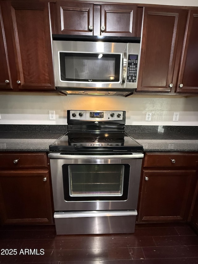 kitchen with appliances with stainless steel finishes, dark brown cabinets, and dark wood-style floors