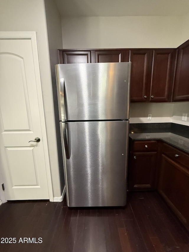 kitchen featuring dark brown cabinets, dark wood-style flooring, and freestanding refrigerator