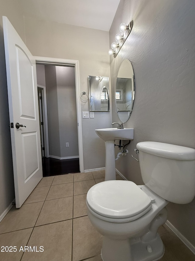 bathroom with baseboards, toilet, and tile patterned floors