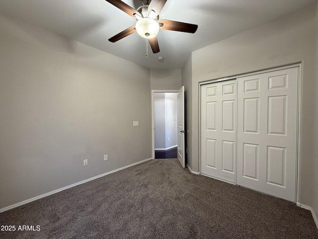 unfurnished bedroom featuring a ceiling fan, baseboards, dark colored carpet, and a closet