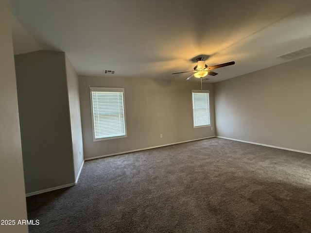 empty room with baseboards, dark carpet, visible vents, and a ceiling fan