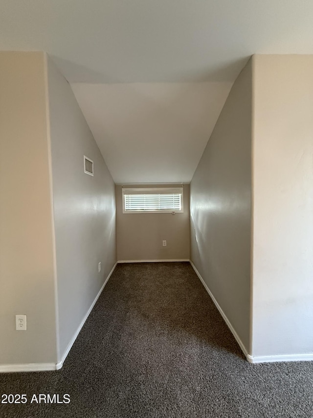 carpeted spare room featuring visible vents, baseboards, and vaulted ceiling