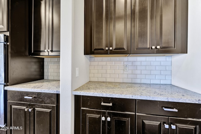 kitchen with light stone counters, dark brown cabinetry, and backsplash