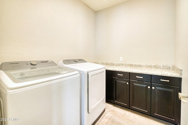 laundry area featuring washer and dryer, cabinets, and light tile patterned floors