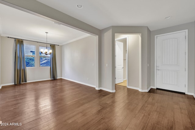 unfurnished room with crown molding, dark hardwood / wood-style flooring, and an inviting chandelier