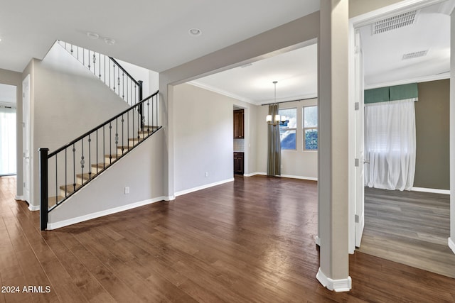 unfurnished living room featuring an inviting chandelier, dark hardwood / wood-style floors, and ornamental molding