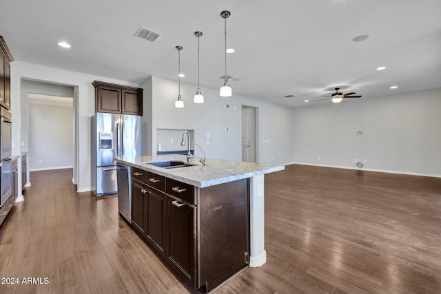 kitchen featuring ceiling fan, a kitchen island with sink, dark wood-type flooring, sink, and hanging light fixtures