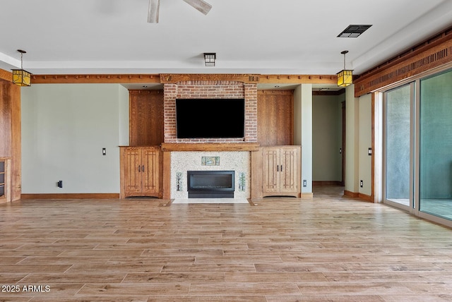 unfurnished living room featuring light wood-type flooring, baseboards, and a large fireplace