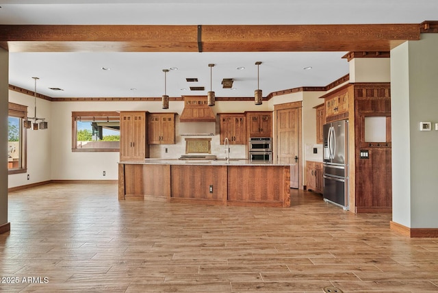 kitchen with stainless steel appliances, premium range hood, brown cabinets, light wood-type flooring, and a sink