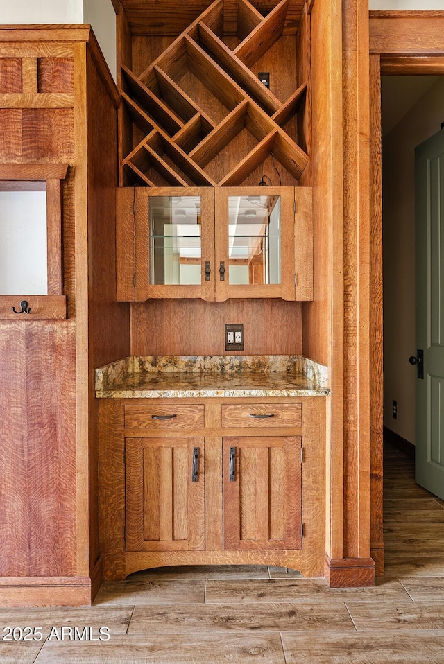 kitchen featuring brown cabinetry, open shelves, light wood-type flooring, and stone countertops