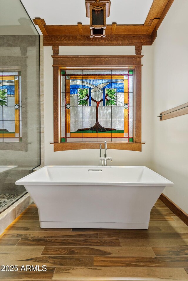 full bath with wood finished floors, a soaking tub, baseboards, and a stall shower